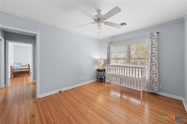 unfurnished bedroom with baseboards, visible vents, ornamental molding, and wood finished floors