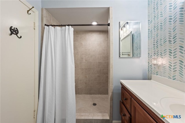 full bath featuring a tile shower and vanity