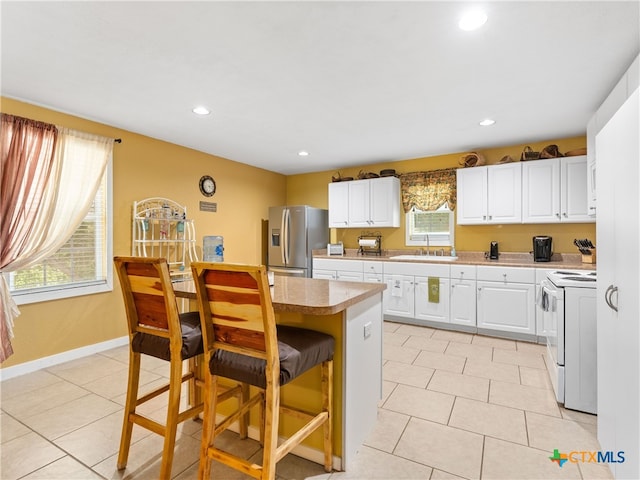 4386 Morningside Way, Canyon Lake, TX 78133 - kitchen with white electric range oven, stainless steel fridge, a breakfast bar, white cabinets, and recessed lighting