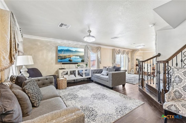 living room featuring dark wood-type flooring, crown molding, and a textured ceiling