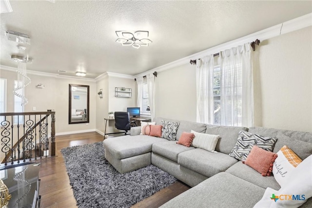 living room featuring dark wood-type flooring, ornamental molding, and a textured ceiling