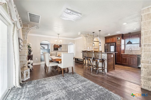 dining space featuring crown molding, sink, a chandelier, and dark hardwood / wood-style flooring