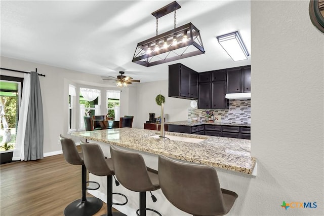 326 Riverview Rd, Mcqueeney, TX 78123 - kitchen with a breakfast bar area, wood finished floors, backsplash, light stone counters, and pendant lighting