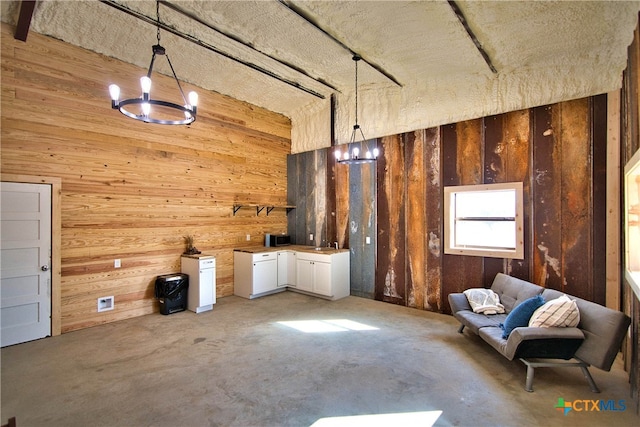 misc room with wood walls, concrete flooring, and a notable chandelier