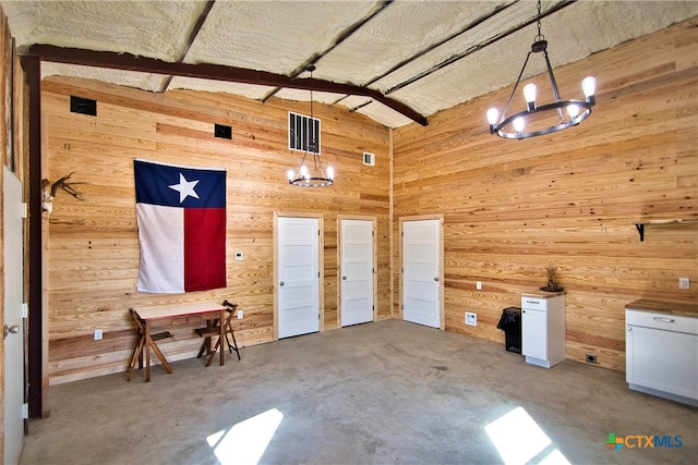 miscellaneous room featuring lofted ceiling with beams, concrete flooring, a chandelier, and wooden walls