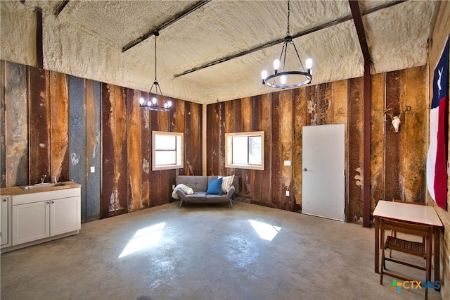 miscellaneous room featuring concrete flooring, sink, and a notable chandelier