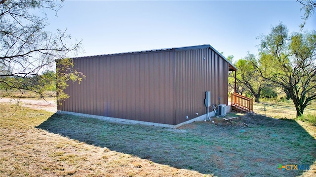 view of outdoor structure featuring central AC unit and a yard