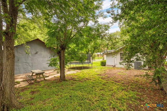 921 S Laurel Ave, Luling, TX 78648 - view of green lawn featuring a trampoline and central AC