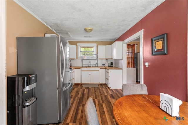 921 S Laurel Ave, Luling, TX 78648 - kitchen with freestanding refrigerator, a textured ceiling, dark wood finished floors, white cabinetry, and a sink