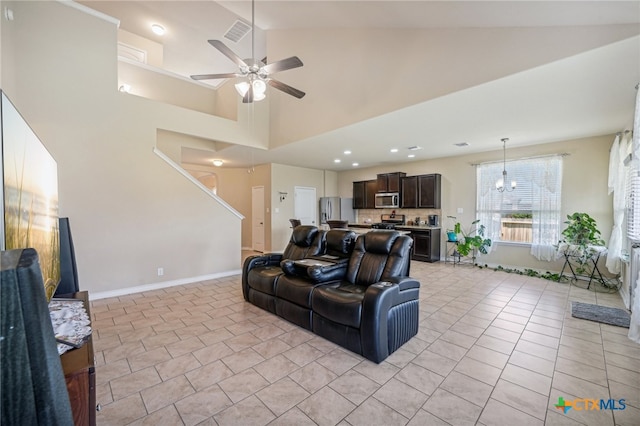 tiled living room featuring high vaulted ceiling and ceiling fan with notable chandelier