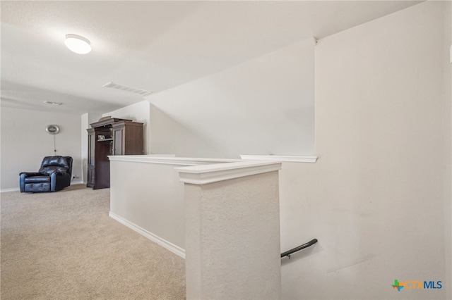 hall featuring lofted ceiling and light carpet