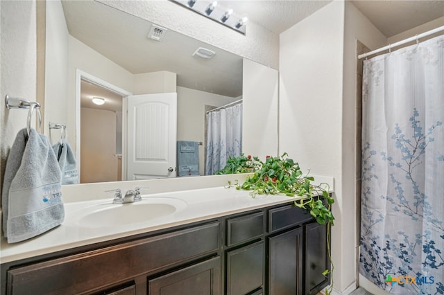 bathroom featuring vanity, a textured ceiling, and curtained shower