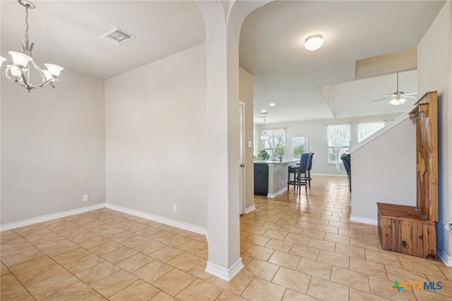 tiled spare room featuring ceiling fan with notable chandelier