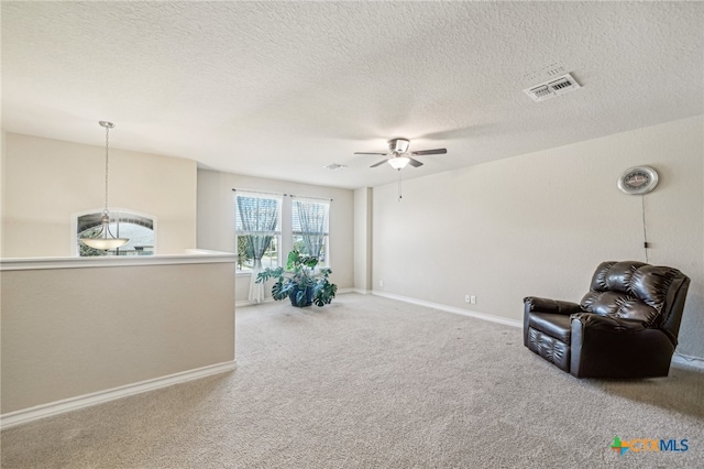 sitting room with a textured ceiling, carpet flooring, and ceiling fan