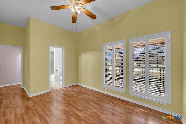 empty room with ceiling fan, wood finished floors, and baseboards