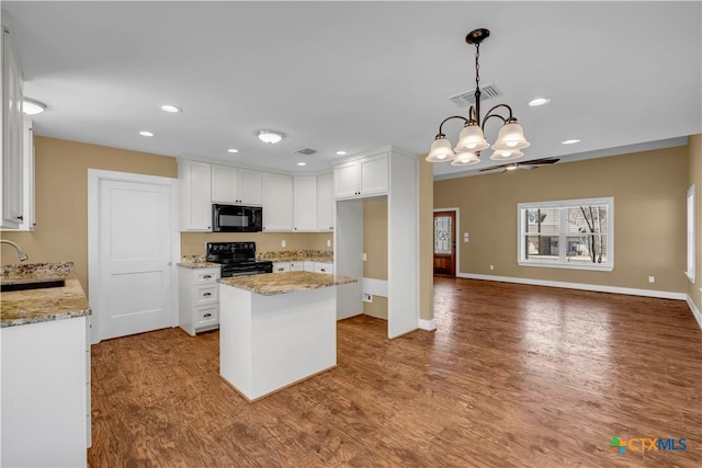 kitchen featuring a center island, visible vents, white cabinets, wood finished floors, and black appliances