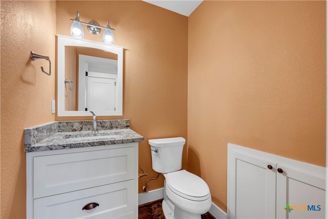 half bath featuring toilet, baseboards, and vanity