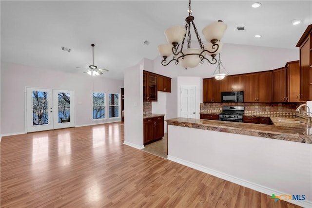 kitchen featuring black microwave, stainless steel gas range oven, a sink, visible vents, and open floor plan