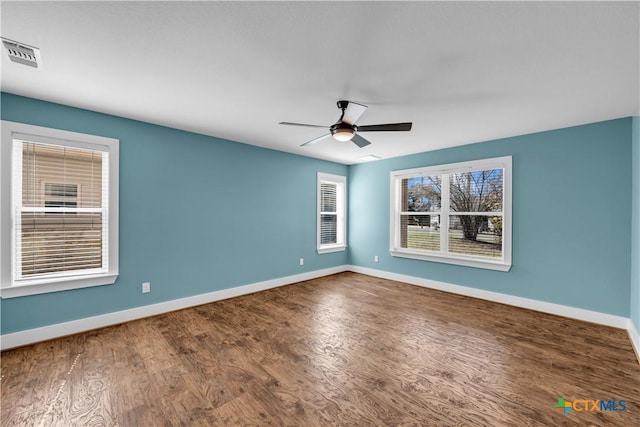 empty room with a ceiling fan, visible vents, baseboards, and wood finished floors