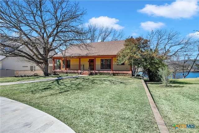 view of front of property featuring covered porch, a front lawn, roof with shingles, and a water view