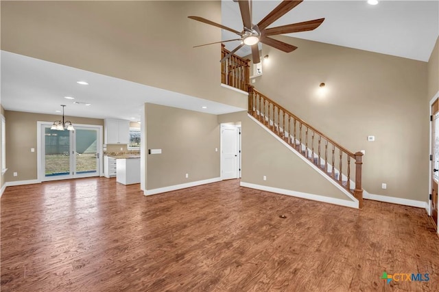 unfurnished living room with baseboards, stairway, and wood finished floors