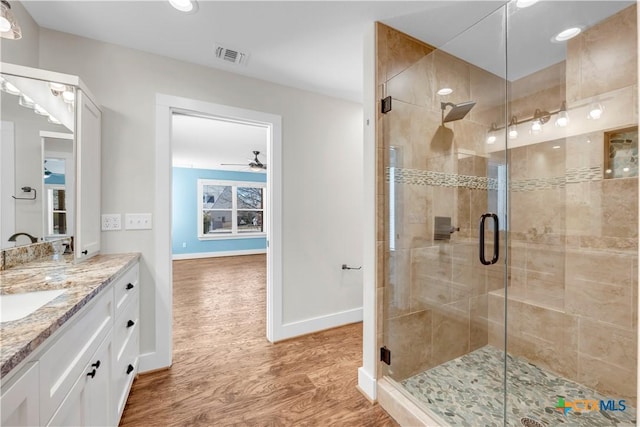 full bathroom with a stall shower, visible vents, wood finished floors, and vanity