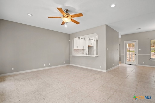 unfurnished living room featuring sink, ceiling fan, and light tile patterned floors