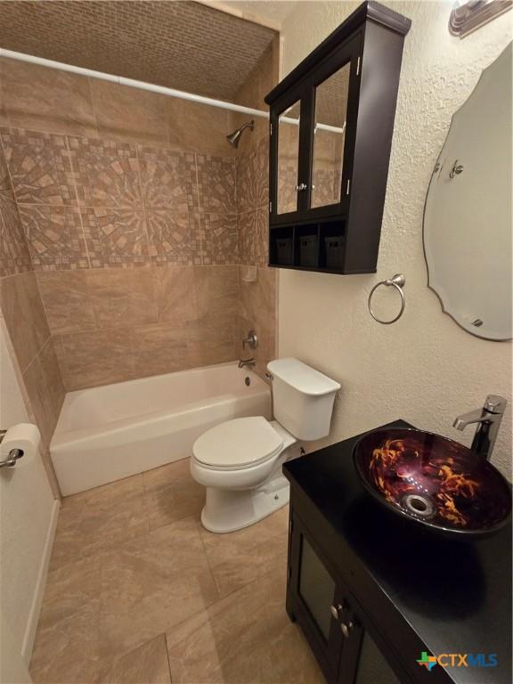 full bathroom featuring tiled shower / bath combo, vanity, and toilet