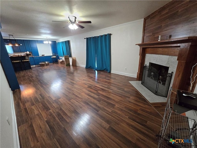 living room featuring ceiling fan with notable chandelier, a tile fireplace, and dark hardwood / wood-style floors