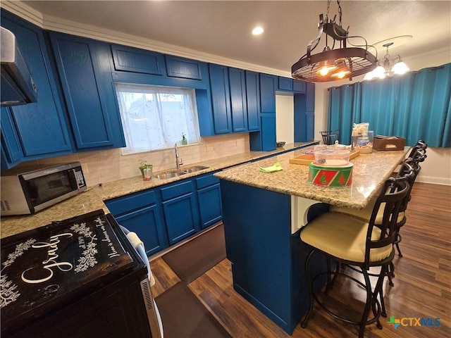 kitchen featuring pendant lighting, blue cabinets, sink, and a kitchen island