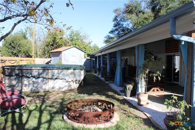 view of yard with a covered pool, a storage unit, and a fire pit