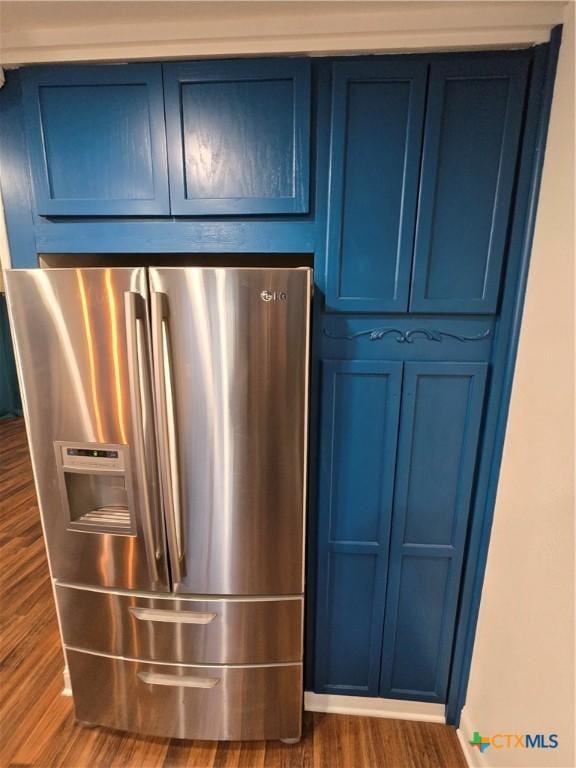 interior details with stainless steel refrigerator with ice dispenser, blue cabinetry, and dark hardwood / wood-style floors