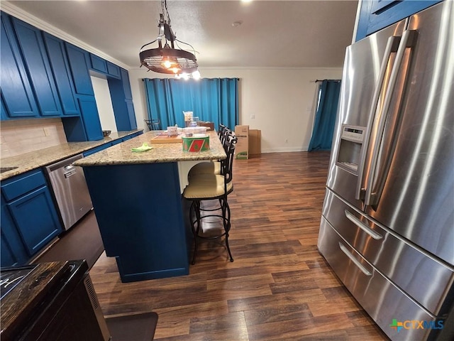 kitchen featuring appliances with stainless steel finishes, a center island, light stone counters, and decorative light fixtures