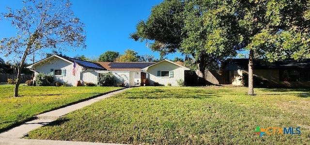 ranch-style house with a front yard and solar panels