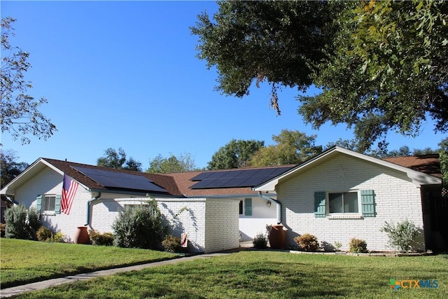 ranch-style house featuring a front lawn and solar panels