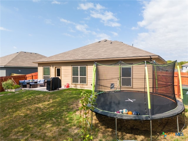 back of property with a lawn, a patio, a trampoline, and an outdoor hangout area