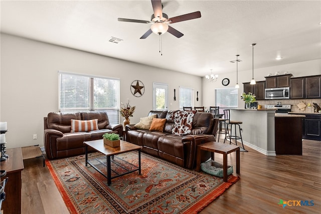 living room featuring ceiling fan with notable chandelier and dark wood-type flooring