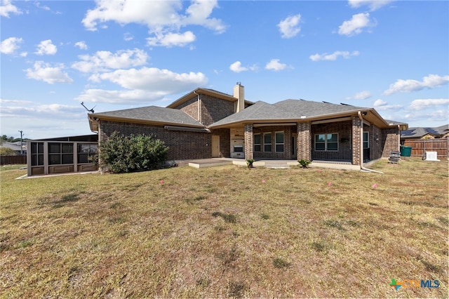 back of property with a sunroom, a patio, and a lawn