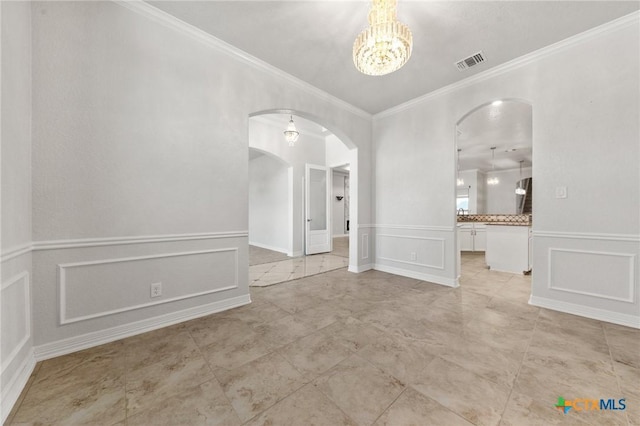 spare room featuring an inviting chandelier and crown molding