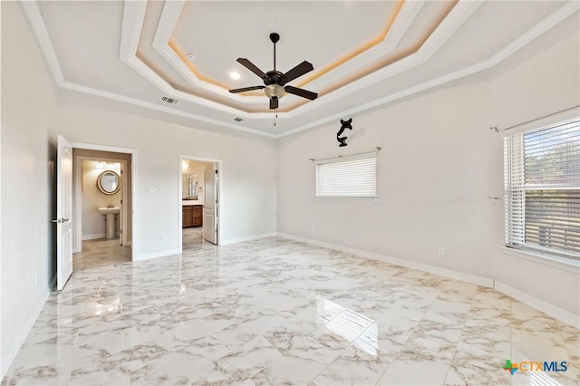 unfurnished bedroom featuring ceiling fan, a raised ceiling, crown molding, and connected bathroom