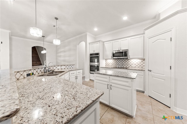 kitchen featuring light stone counters, stainless steel appliances, sink, pendant lighting, and white cabinetry