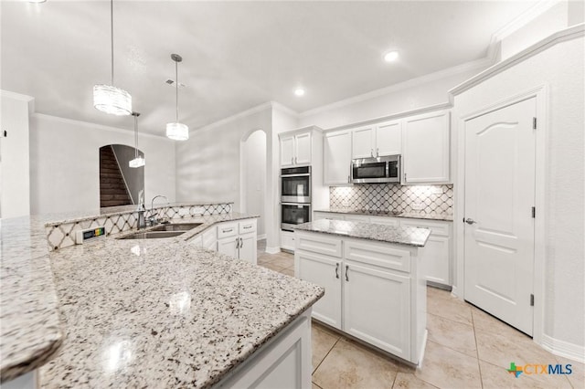 kitchen with light stone countertops, appliances with stainless steel finishes, sink, decorative light fixtures, and white cabinets