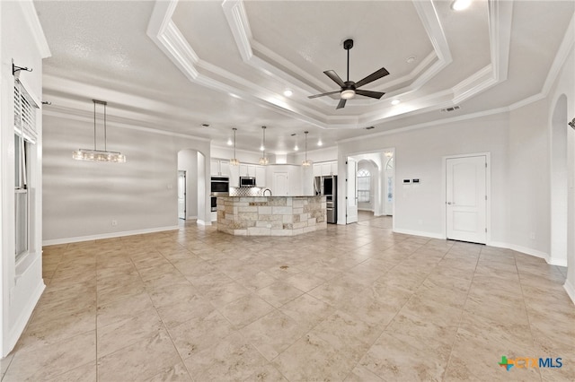 unfurnished living room with a tray ceiling, crown molding, and ceiling fan