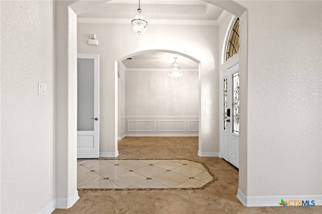 hall featuring a notable chandelier, light tile patterned flooring, and ornamental molding