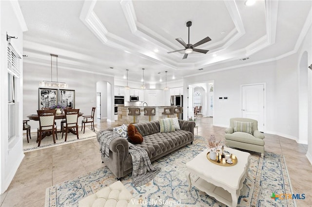 tiled living room featuring a raised ceiling, ceiling fan, and ornamental molding