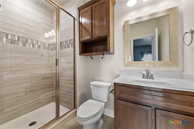 bathroom featuring tile patterned flooring, vanity, toilet, and walk in shower