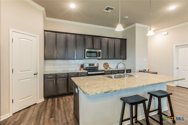 7106 Boulder Star Way, Temple, TX 76502 - kitchen featuring appliances with stainless steel finishes, a sink, ornamental molding, dark wood finished floors, and a breakfast bar area