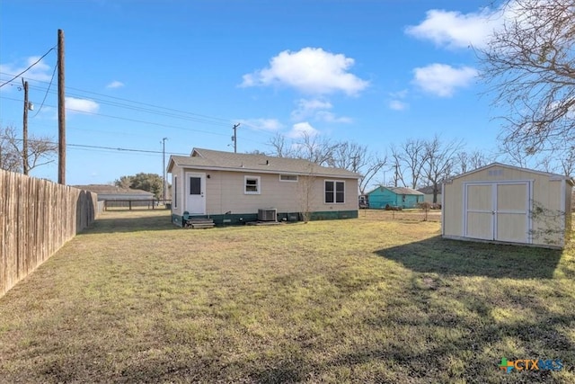 back of property featuring a yard, central AC unit, and a storage shed