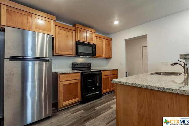 kitchen featuring sink, black appliances, light stone counters, backsplash, and dark wood-type flooring