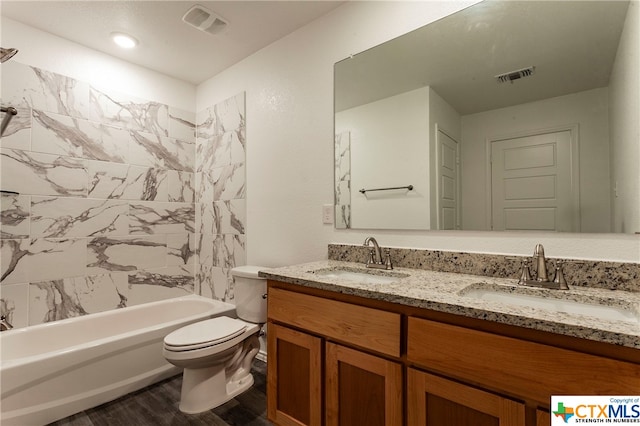 full bathroom featuring hardwood / wood-style flooring, vanity, toilet, and tiled shower / bath